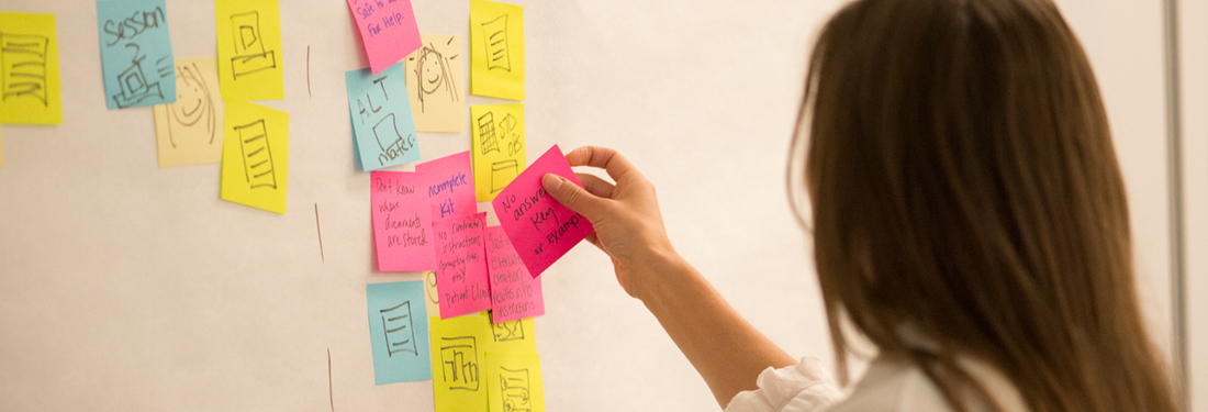 Woman Putting Sticky Notes on Wall | Virginia Mason Institute