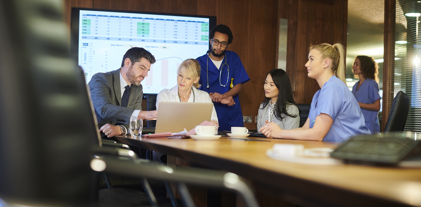 Medical Professionals Looking at Computer with Presentation in the Background | Virginia Mason Institute